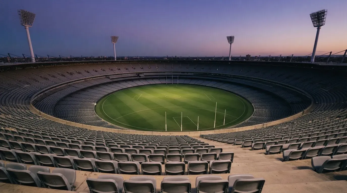 An empty football stadium with floodlight masts at dusk