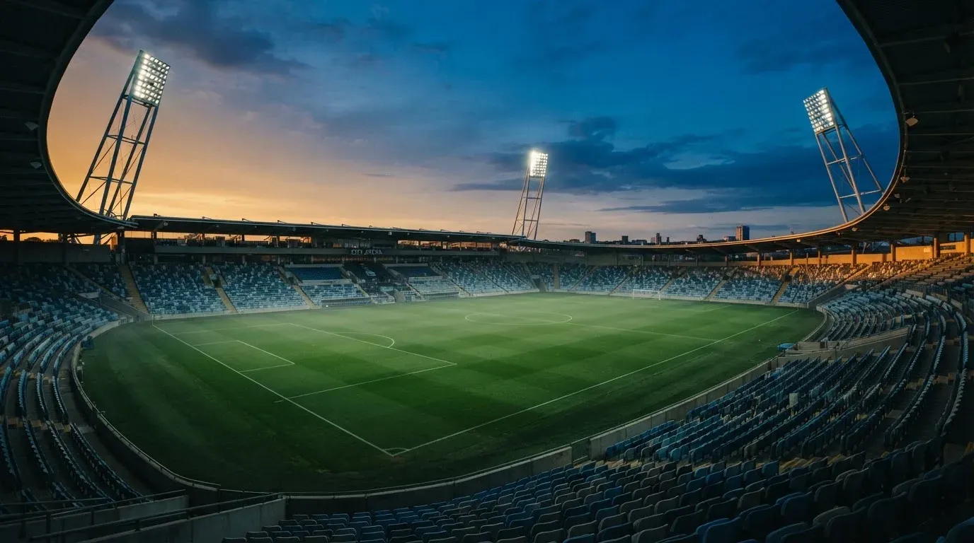 An empty football stadium with floodlight masts at dusk