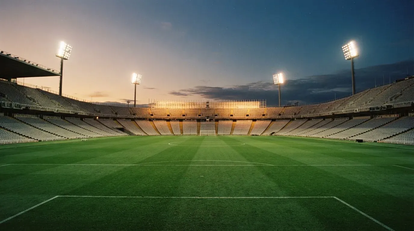 An empty football stadium with floodlight masts at dusk