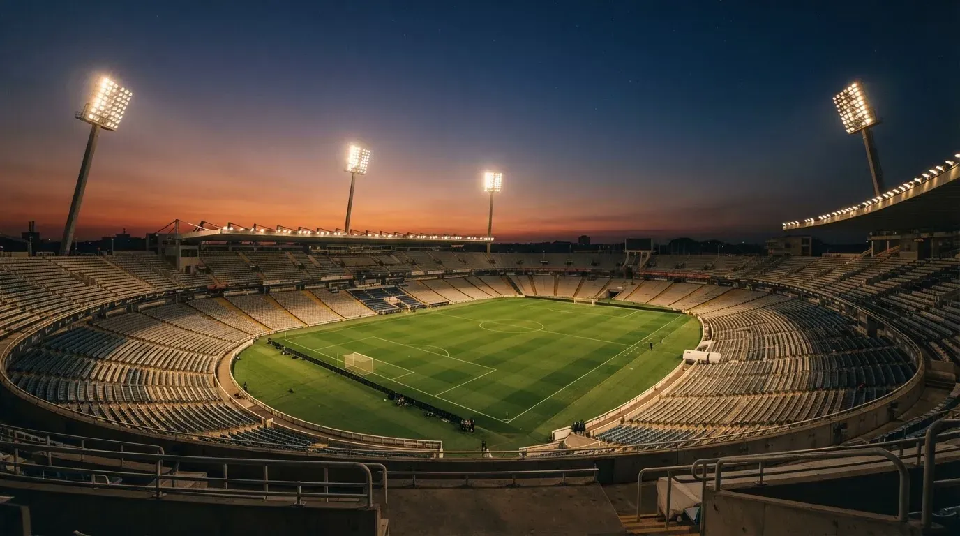 An empty football stadium with floodlight masts at dusk
