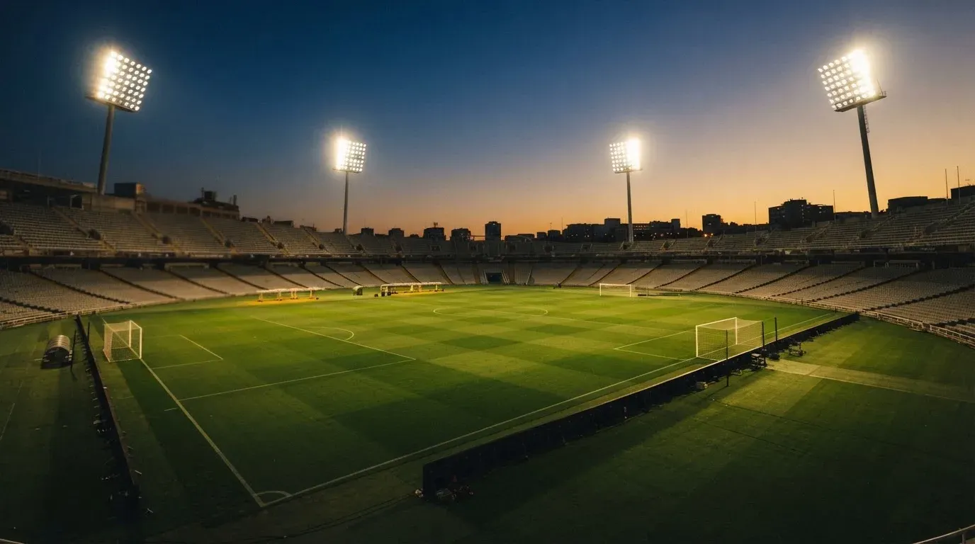 An empty football stadium with floodlight masts at dusk