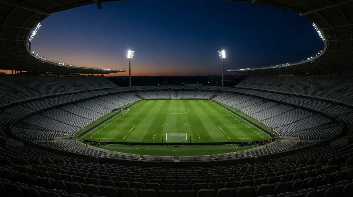An empty football stadium with floodlight masts at dusk