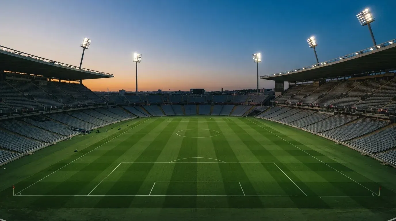An empty football stadium with floodlight masts at dusk