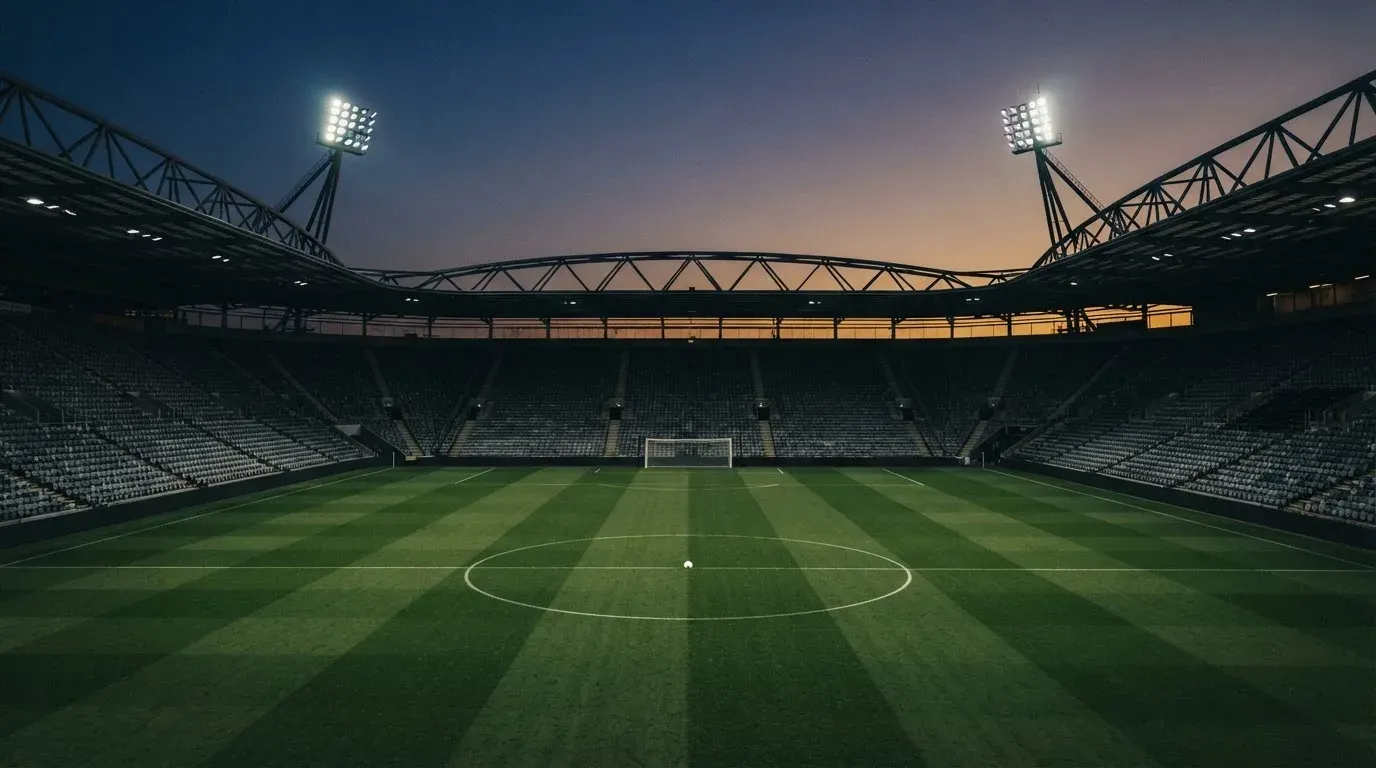 An empty football stadium with floodlight masts at dusk
