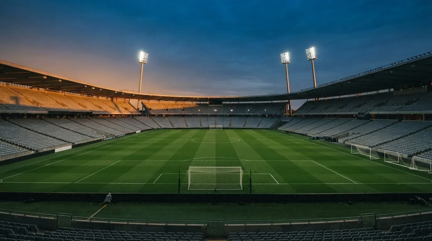 An empty football stadium with floodlight masts at dusk