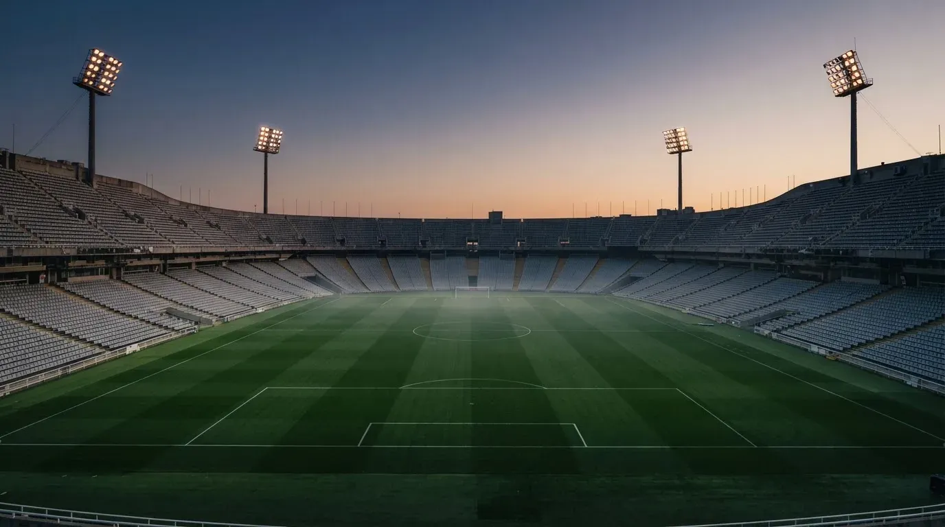 An empty football stadium with floodlight masts at dusk