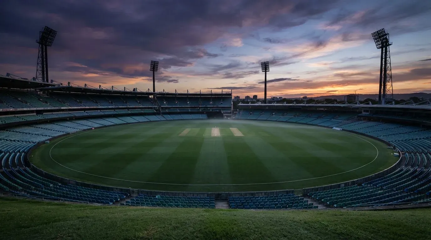 An empty football stadium with floodlight masts at dusk