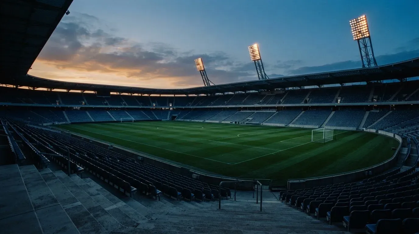 An empty football stadium with floodlight masts at dusk