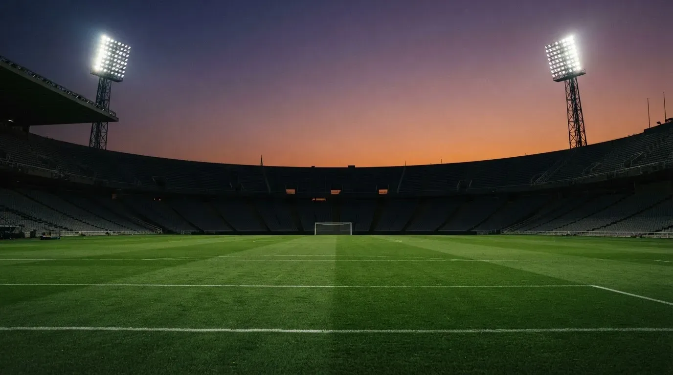 An empty football stadium with floodlight masts at dusk