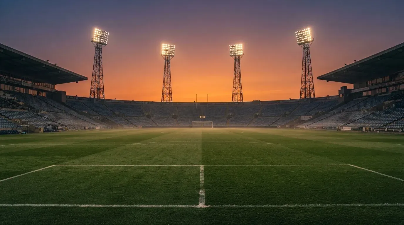 An empty football stadium with floodlight masts at dusk
