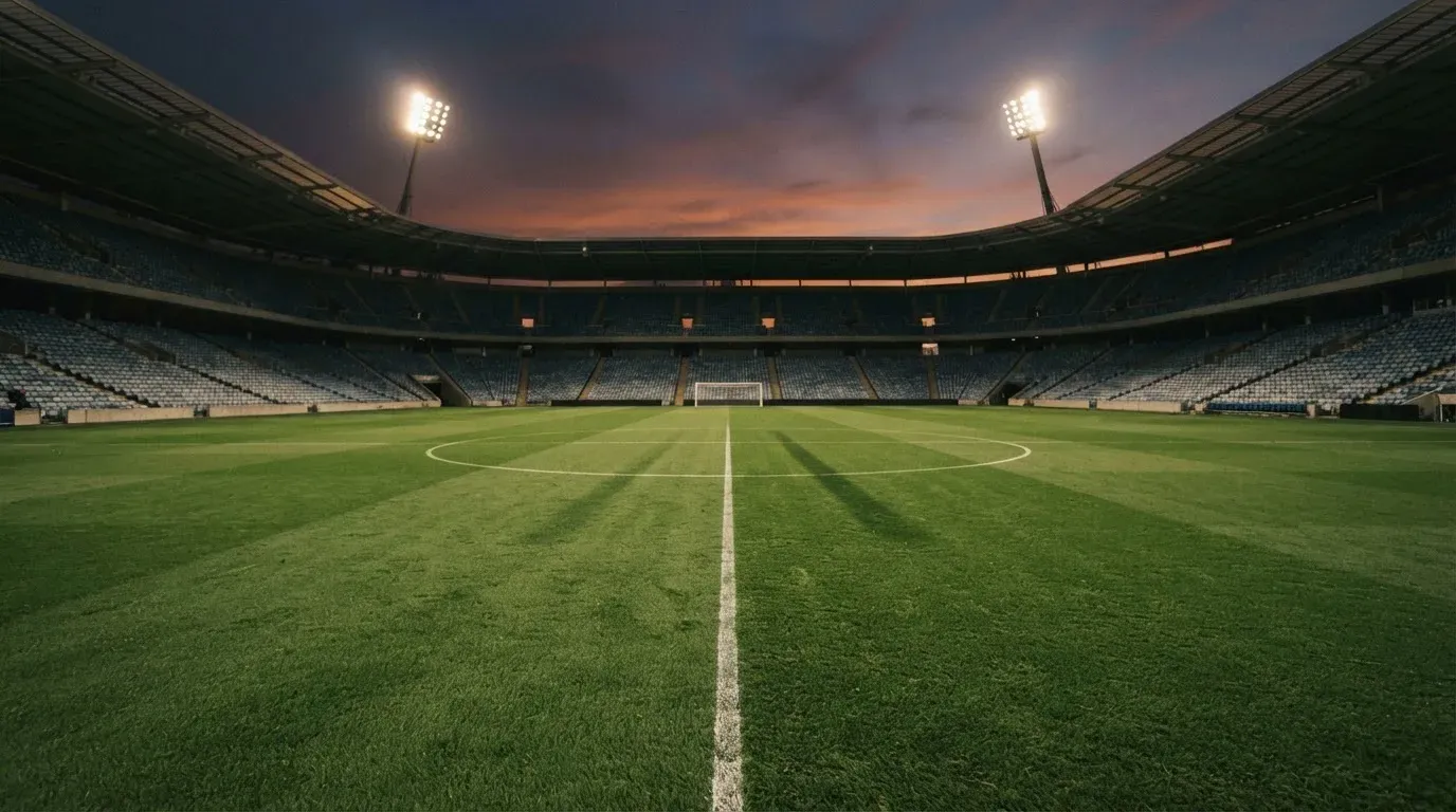 An empty football stadium with floodlight masts at dusk