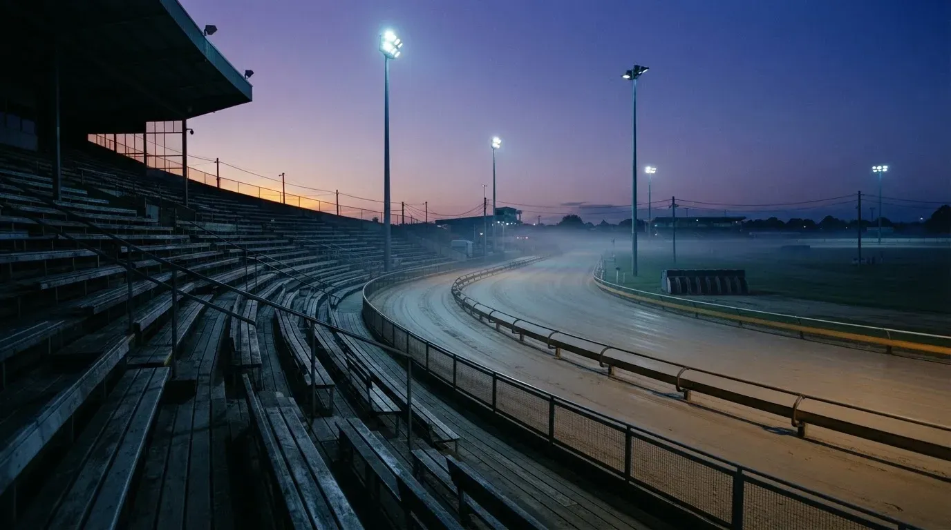 An empty football stadium with floodlight masts at dusk