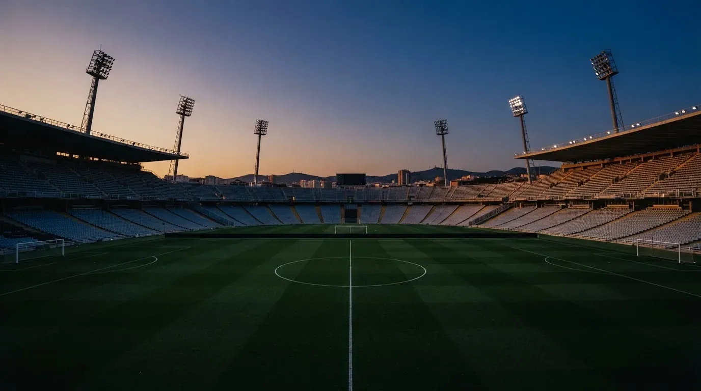 An empty football stadium with floodlight masts at dusk