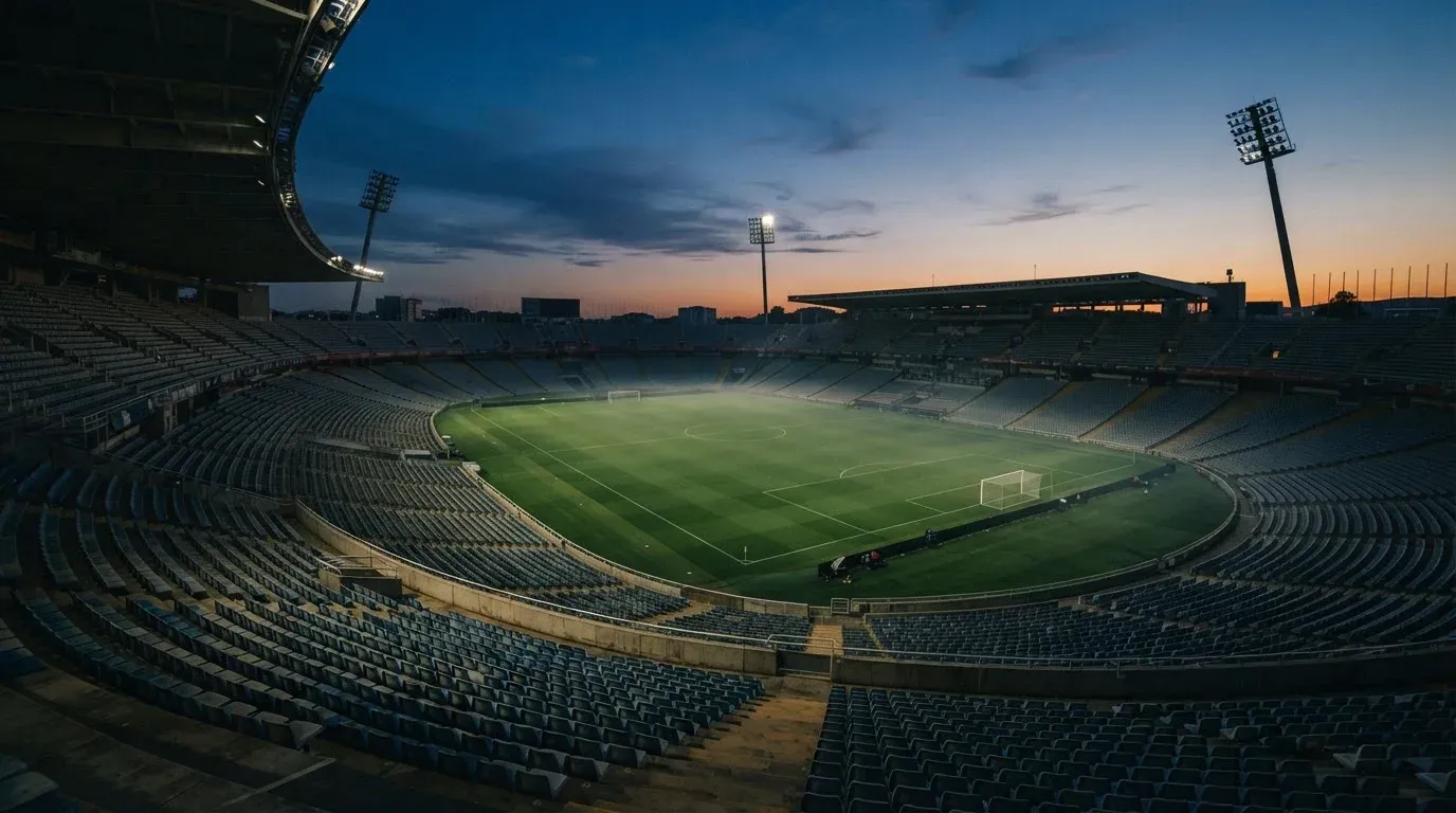 An empty football stadium with floodlight masts at dusk