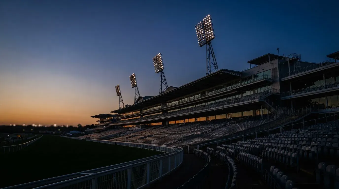 An empty football stadium with floodlight masts at dusk