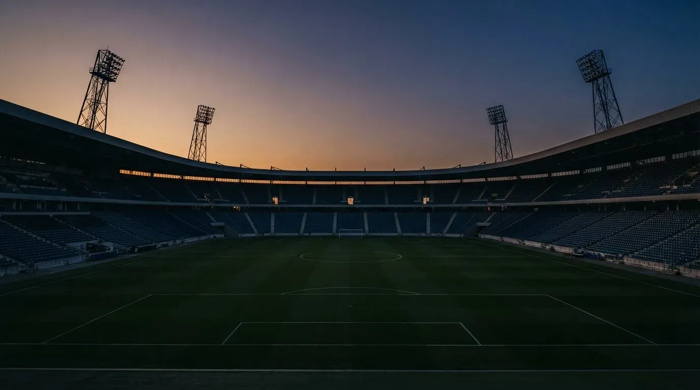 An empty football stadium with floodlight masts at dusk