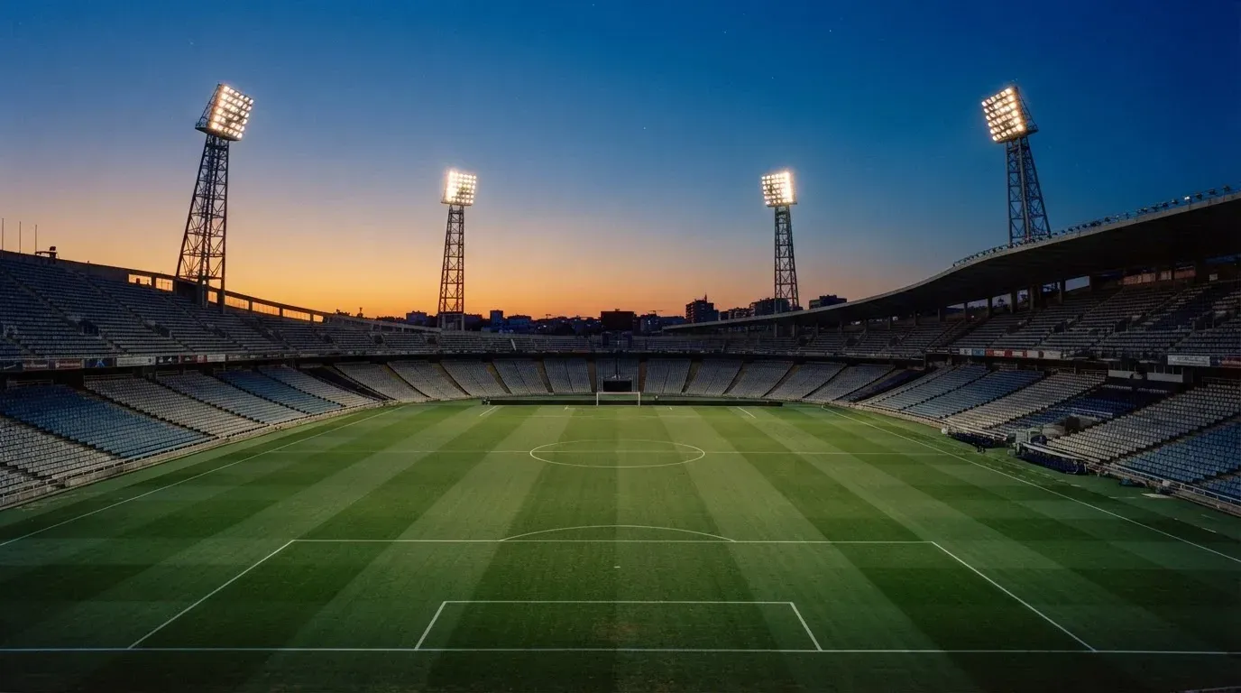 An empty football stadium with floodlight masts at dusk
