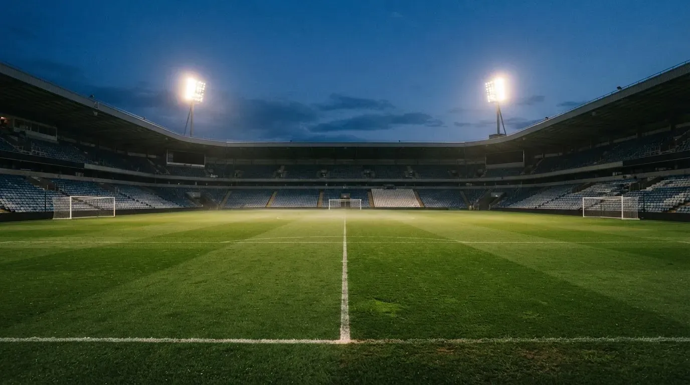 An empty football stadium with floodlight masts at dusk