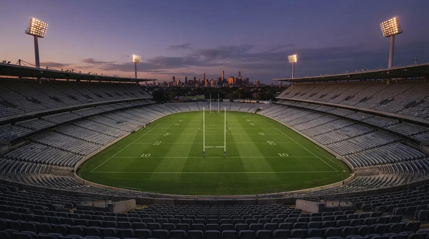 An empty football stadium with floodlight masts at dusk
