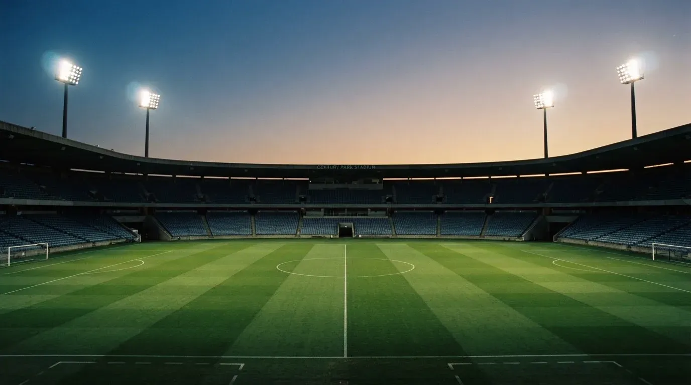 An empty football stadium with floodlight masts at dusk