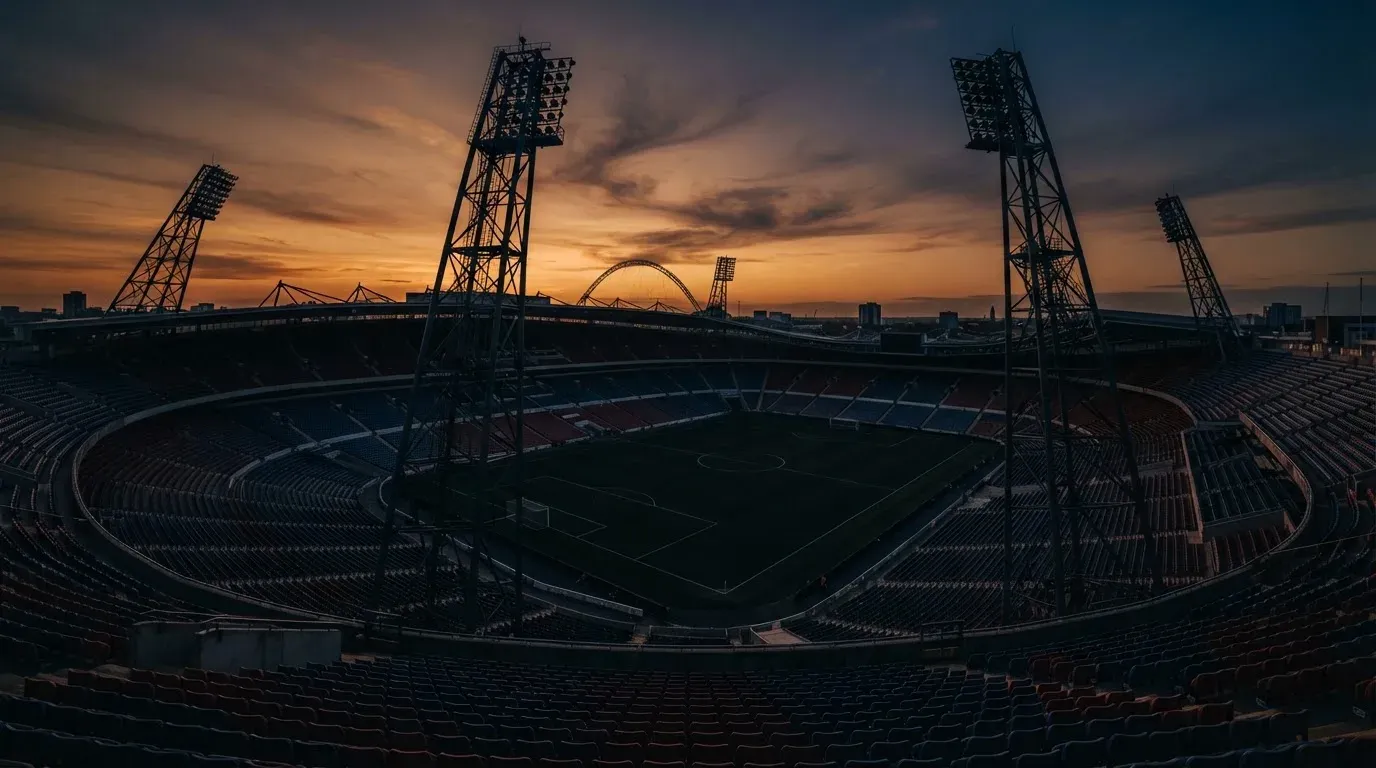 An empty football stadium with floodlight masts at dusk
