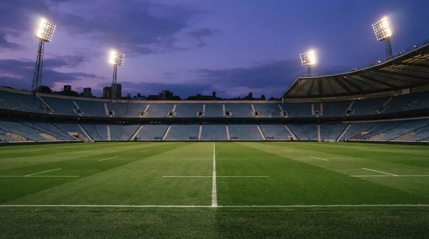 An empty football stadium with floodlight masts at dusk
