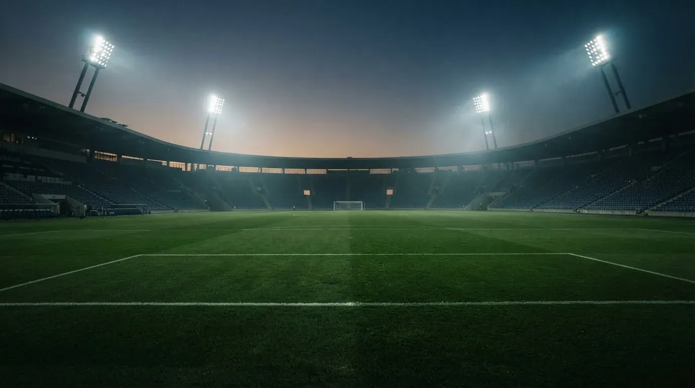 An empty football stadium with floodlight masts at dusk