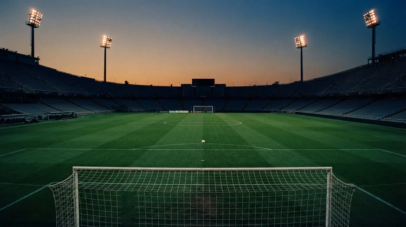 An empty football stadium with floodlight masts at dusk