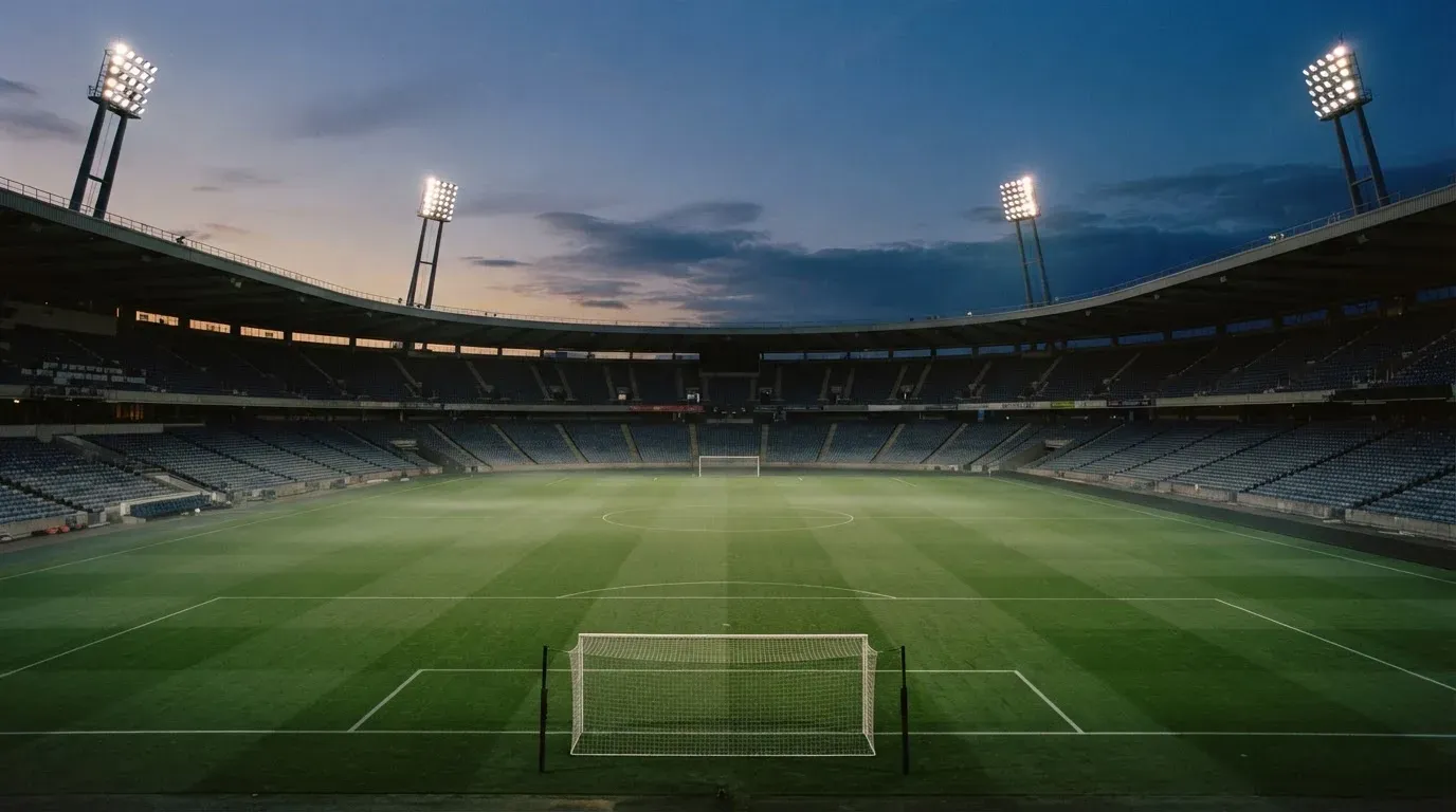An empty football stadium with floodlight masts at dusk