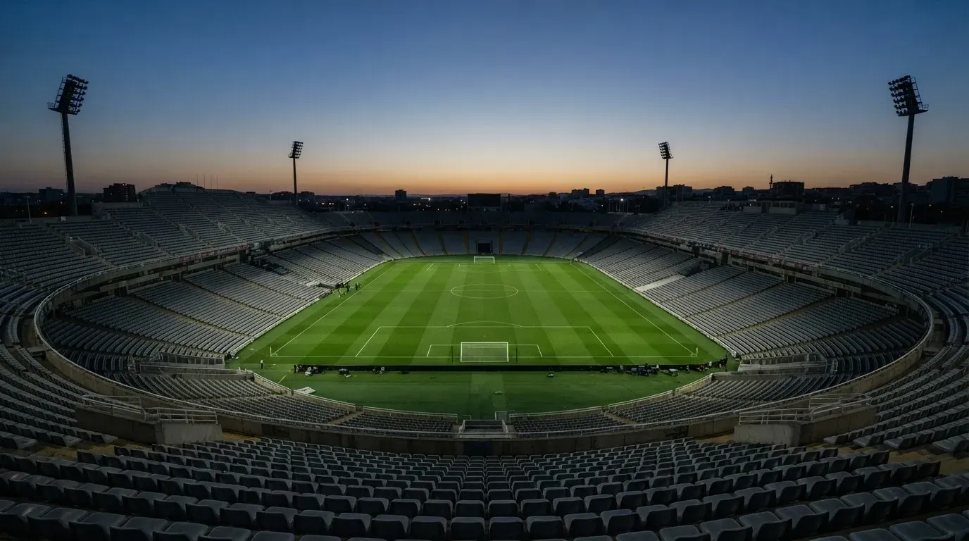 An empty football stadium with floodlight masts at dusk