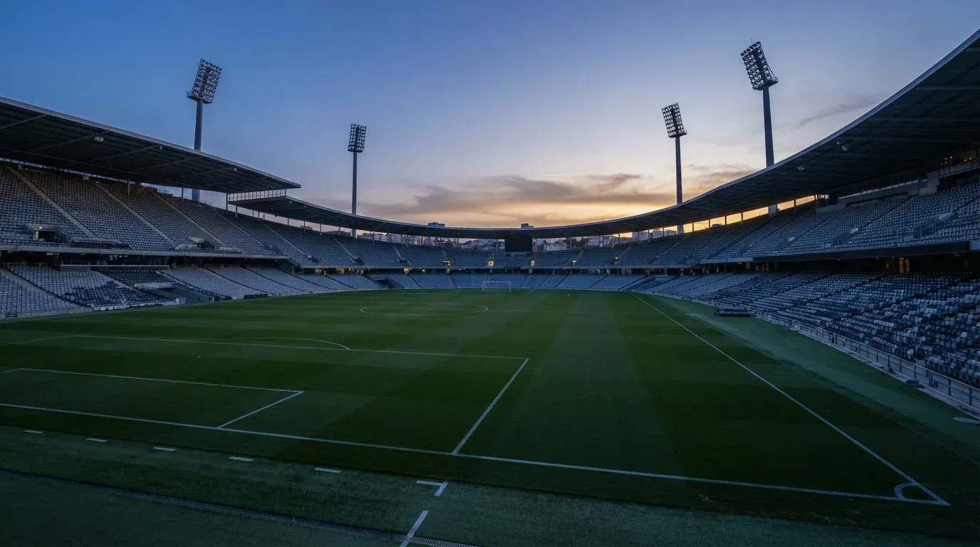 An empty football stadium with floodlight masts at dusk