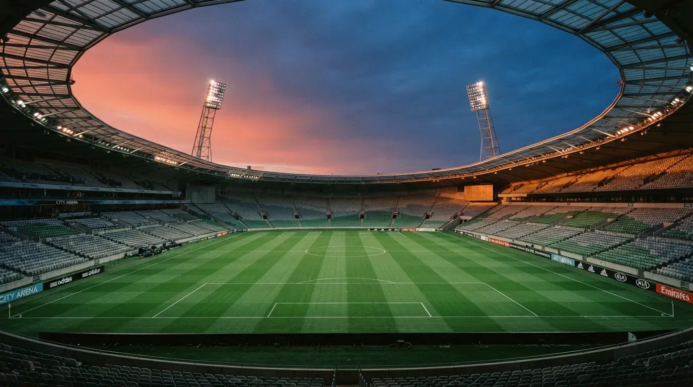 An empty football stadium with floodlight masts at dusk