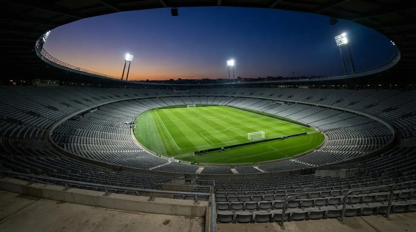An empty football stadium with floodlight masts at dusk