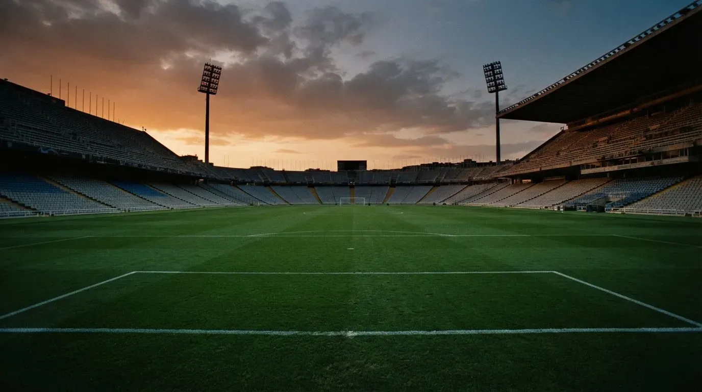 An empty football stadium with floodlight masts at dusk