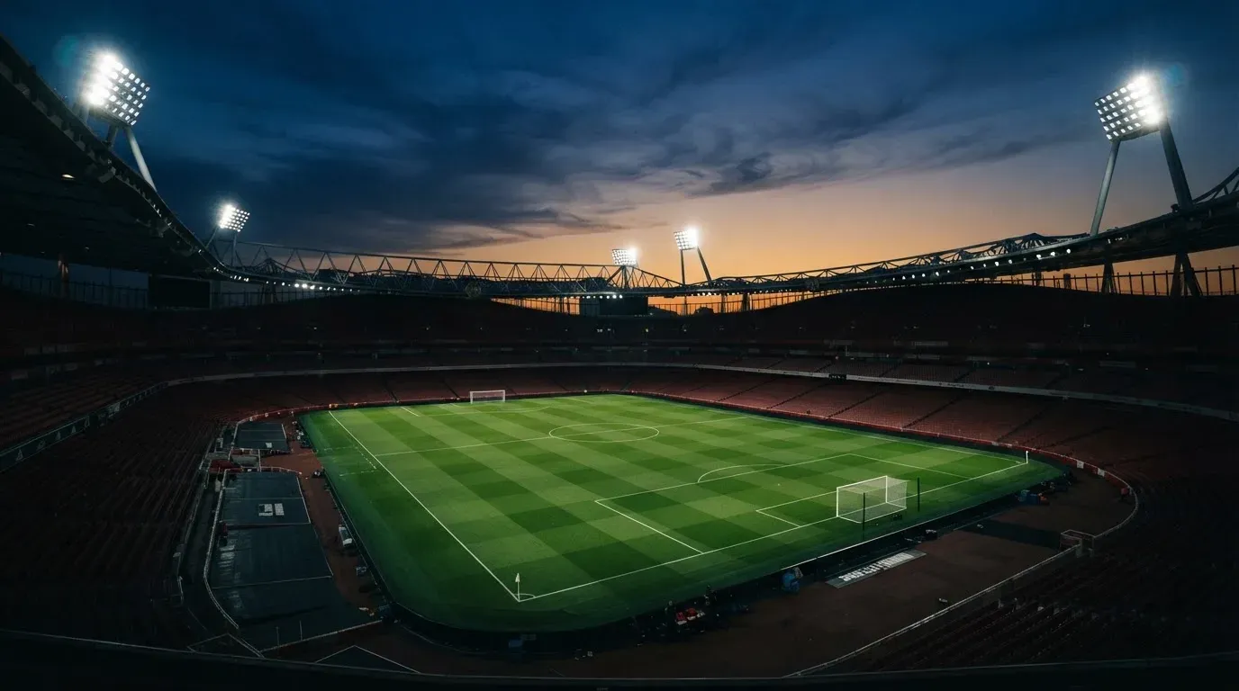 An empty football stadium with floodlight masts at dusk