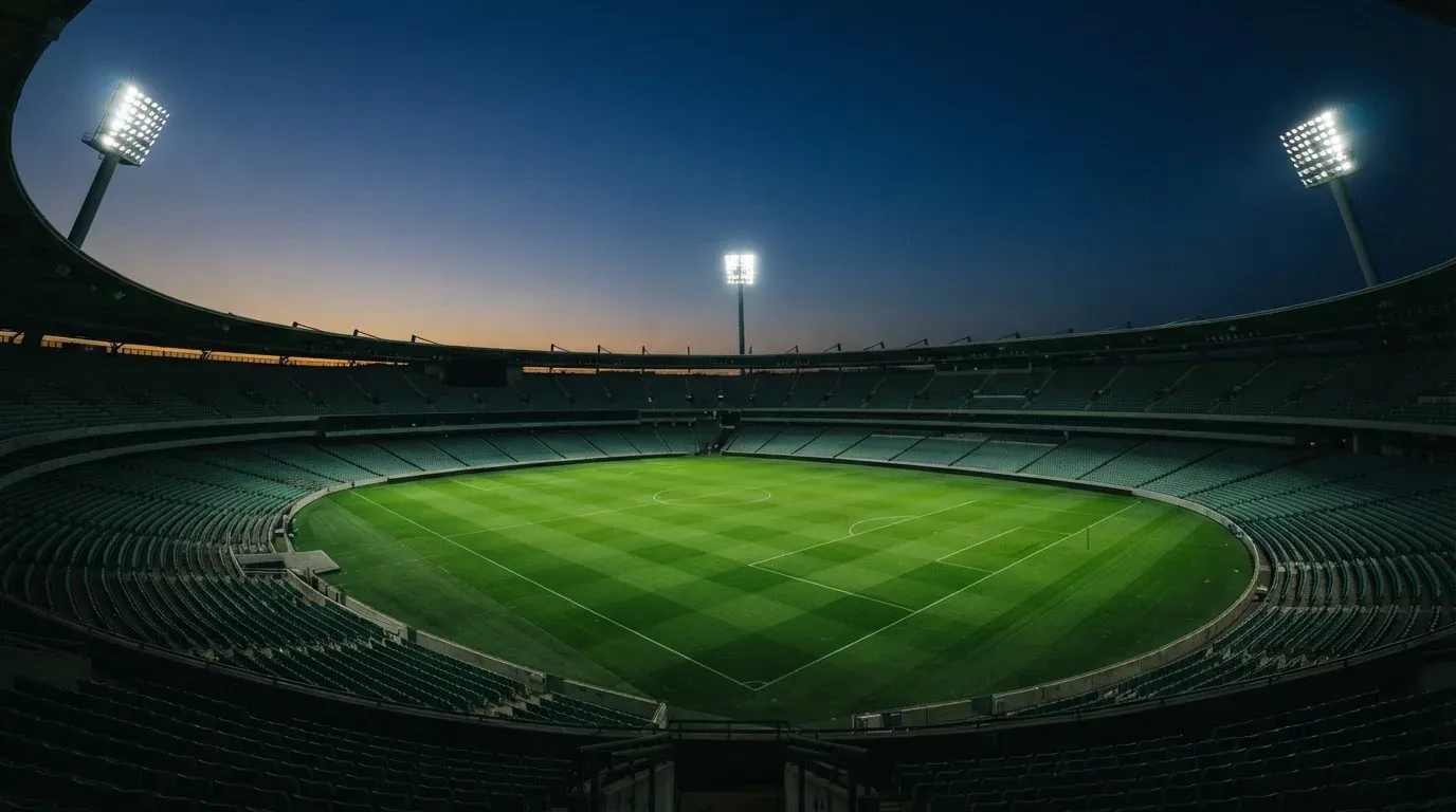 An empty football stadium with floodlight masts at dusk