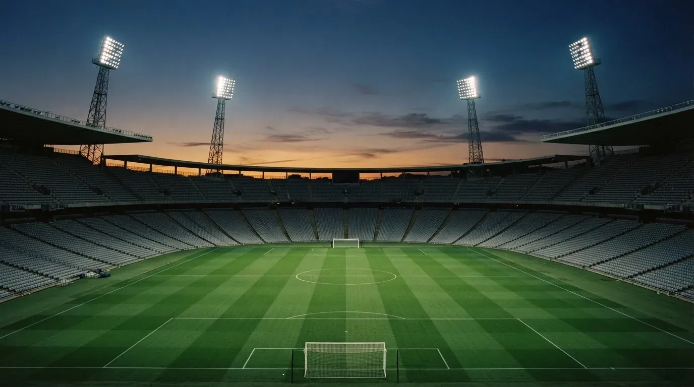 An empty football stadium with floodlight masts at dusk