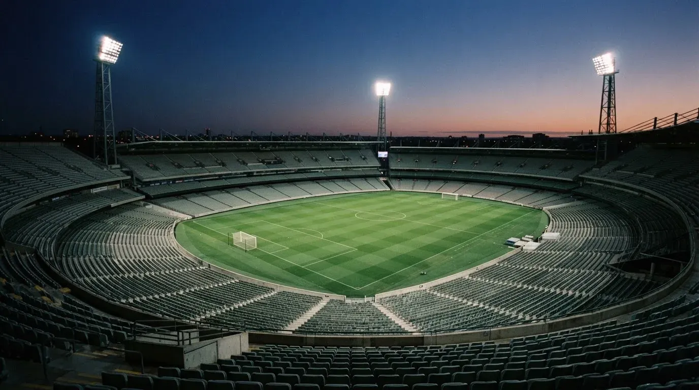 An empty football stadium with floodlight masts at dusk