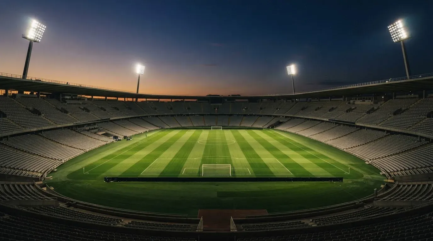 An empty football stadium with floodlight masts at dusk