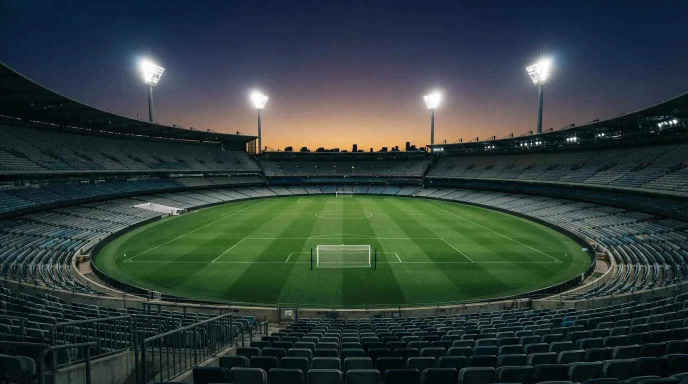 An empty football stadium with floodlight masts at dusk