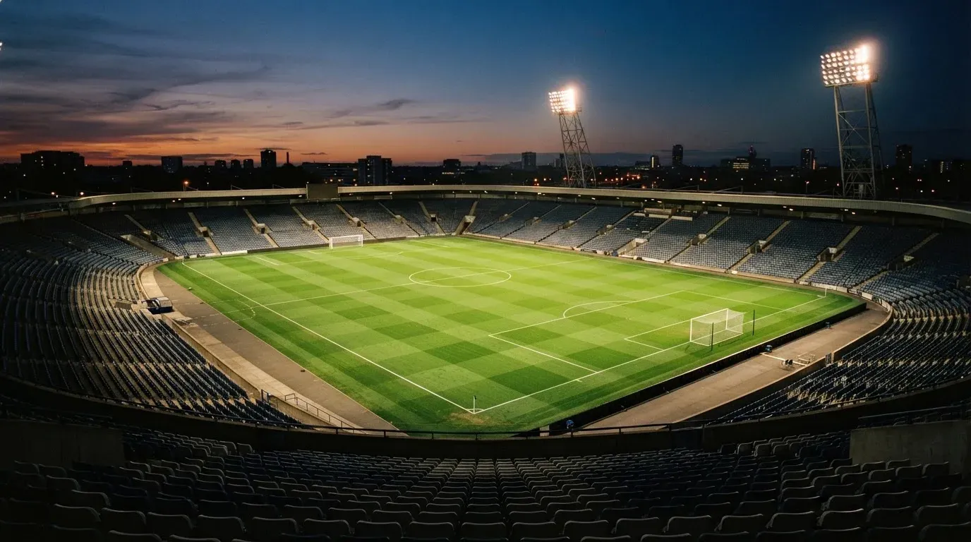 An empty football stadium with floodlight masts at dusk