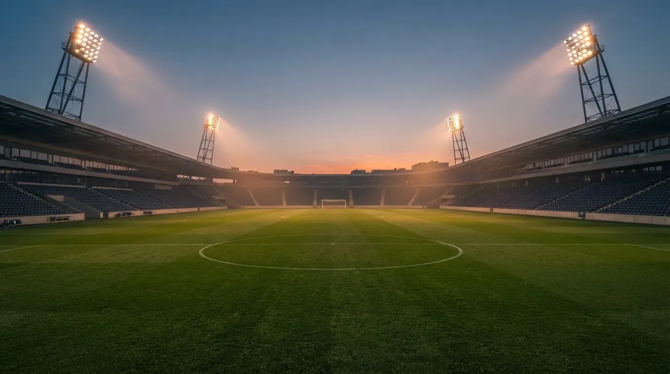 An empty football stadium with floodlight masts at dusk
