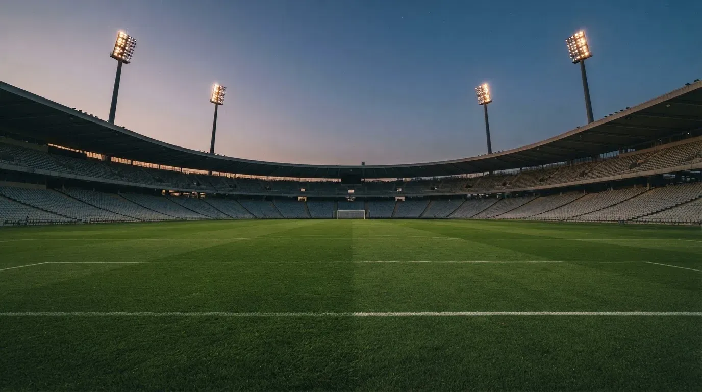 An empty football stadium with floodlight masts at dusk