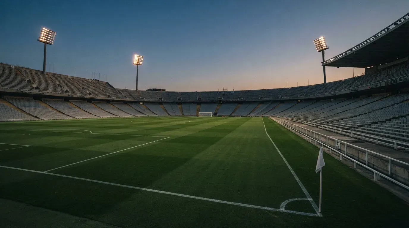 An empty football stadium with floodlight masts at dusk