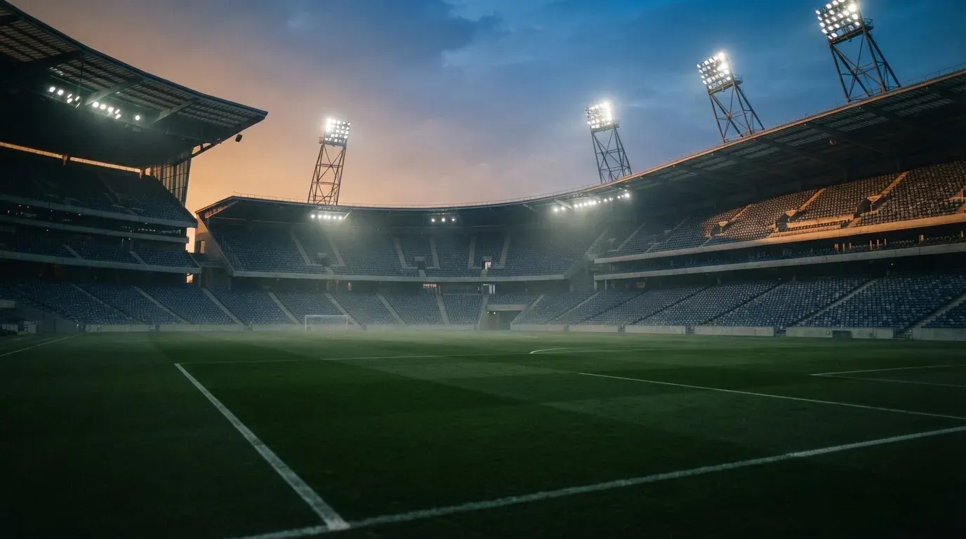 An empty football stadium with floodlight masts at dusk