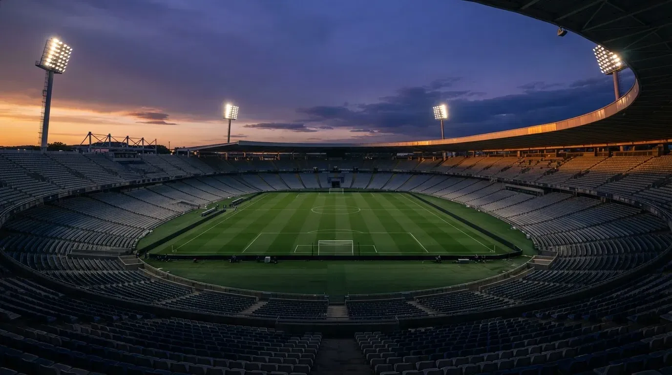 An empty football stadium with floodlight masts at dusk